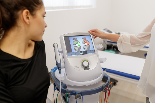Patient looking at ultrasound therapy simulation with therapist on medical device screen