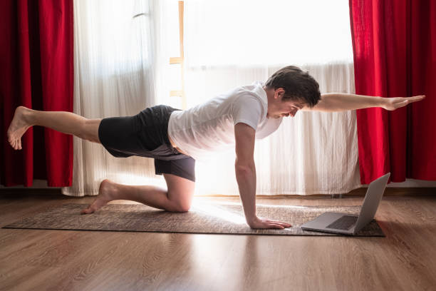 homem pratica yoga asana chakravakasana ou pose de pássaro na sala de estar - stretching yoga men good posture - fotografias e filmes do acervo