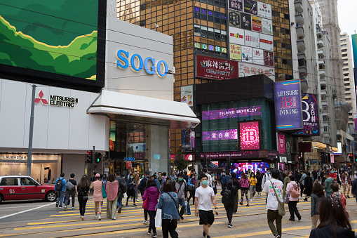 Hong Kong, Hong Kong - April 8, 2020 : People wearing face masks walk past Hennessy Road in Causeway Bay Shopping District, Hong Kong.