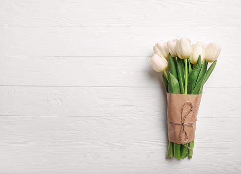 White tulips bouquet on white wooden background. Copy space