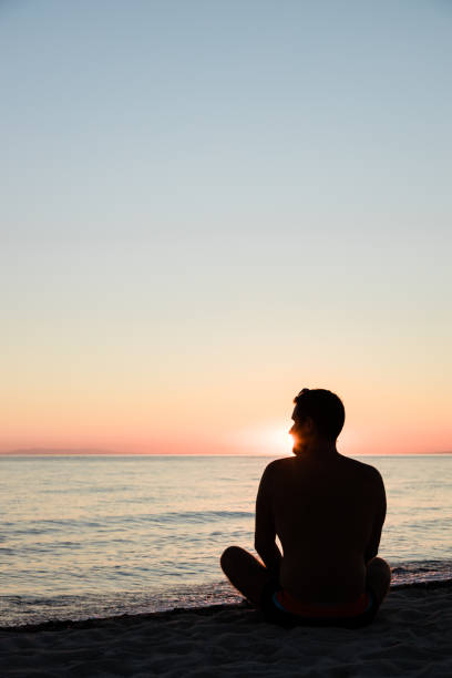istock Young man enjoying sunset on the beach 1218013030