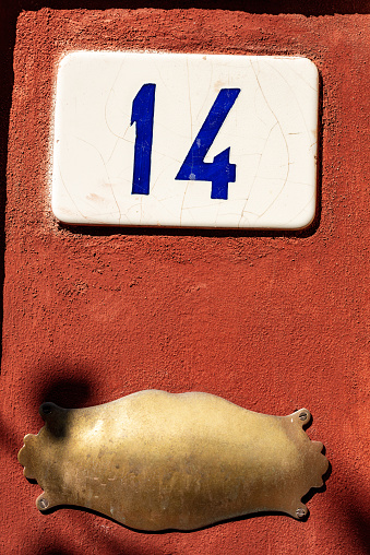 Old house number fourteen and an empty brass plaque with copy space on the red wall, Liguria, Italy, Europe