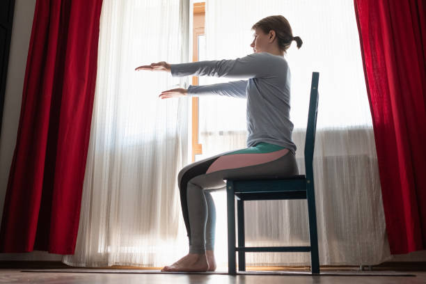istock Beautiful young girl doing exercises at home using chair. 1218015759
