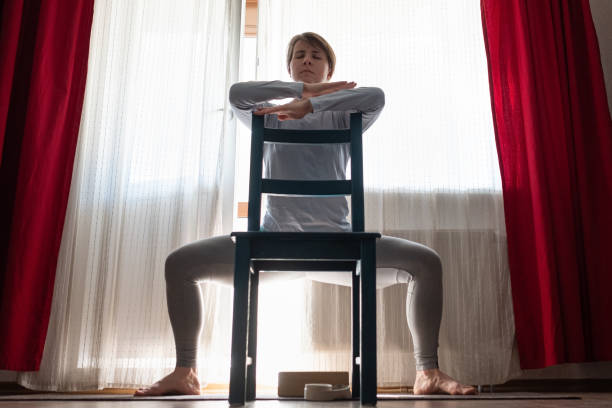 istock girl doing Goddess Pose temple or sumo pose, stupasana, using chair 1218017095