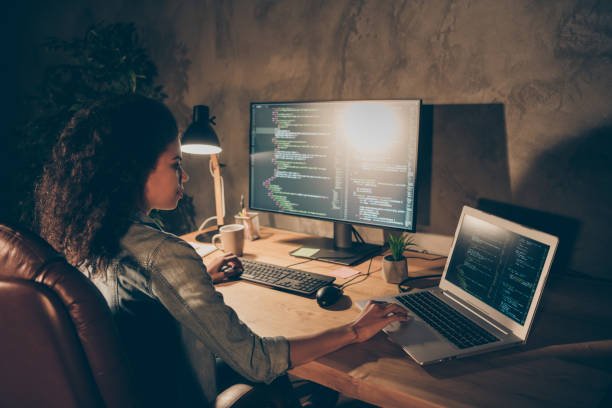 istock Back rear spine view photo focused skilled afro american software developer sit table desk evening start-up office use computer work binary web code testing operating system in workstation 1218020241
