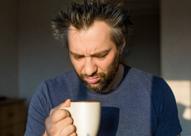 Funny man after awakening looking at his a big cup. Close up funny man after awakening looking at his a big cup of coffee or tea. bad coffee stock pictures, royalty-free photos & images