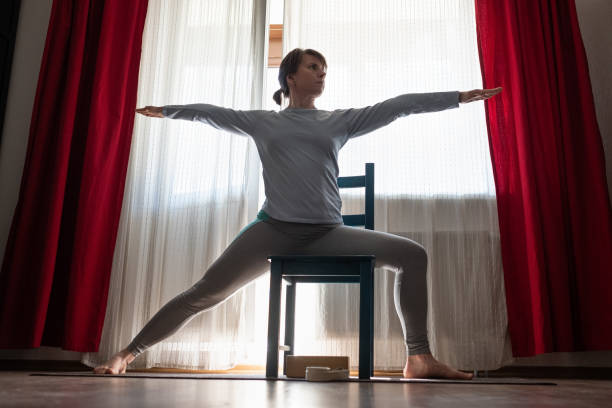 istock Young yoga woman doing warrior pose using chair. 1218026560
