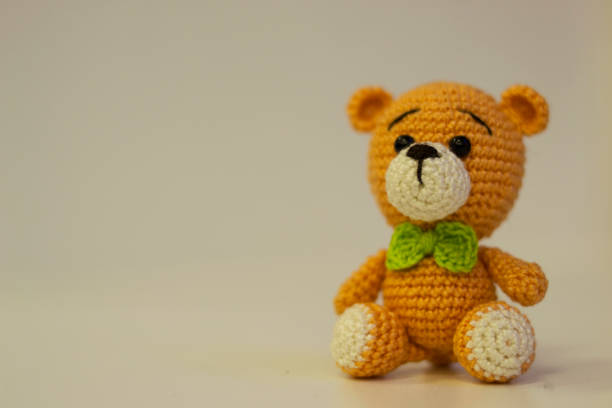 istock Amigurumi orange bear with a green bow sitting on a white background. Needlework concept. 1218026881