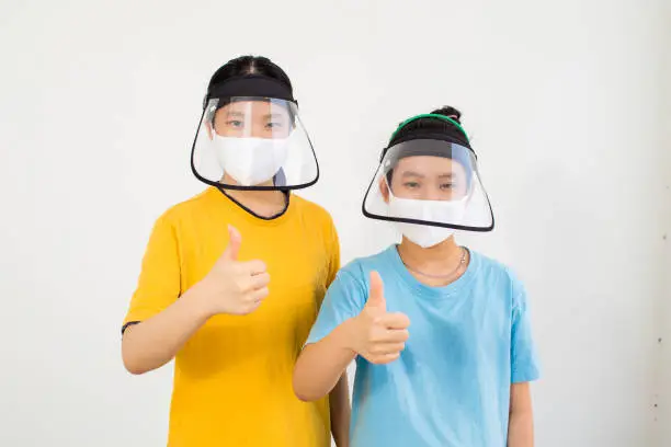 Two Vietnamese girls wearing hat with face shield and mask for protect corona virus outbreak on a white background
