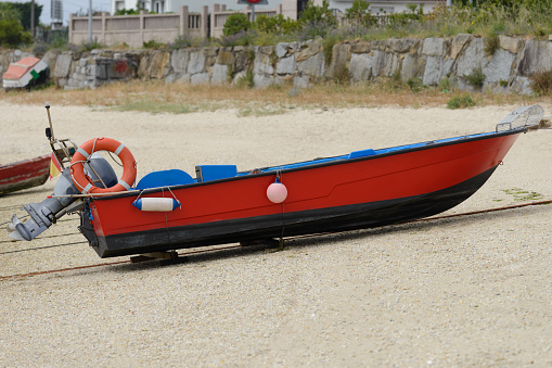 image of red wooden fishing motor boat dries ashore