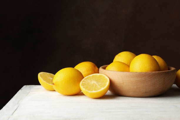 istock Wooden bowl and lemons against brown background, space for text 1218034286