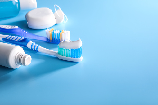 Toothbrush with toothpaste and other dental products on blue backdround