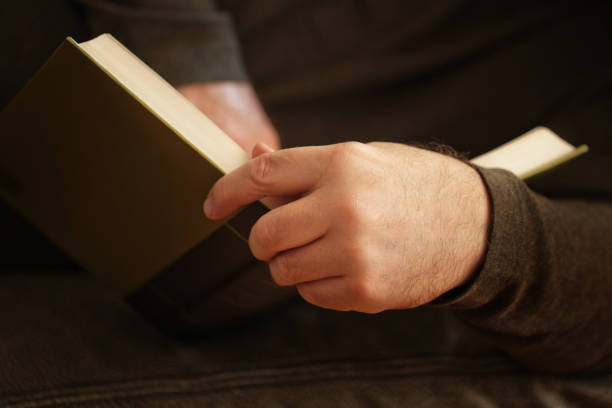 Man reading a book while sitting comfortably at sofa and enjoying weekend