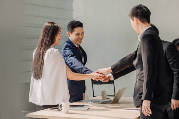 istock young Asian business people putting their hands together. Stack of hands. Unity and teamwork concept. Teamwork Join Hands Support Together Concept 1218037109