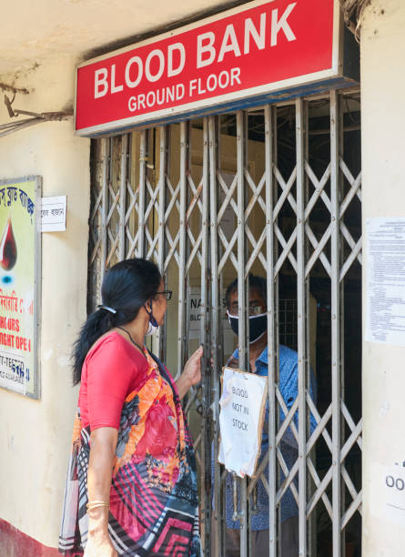 A Blood Bank in Kolkata during COVID-19 lockdown in city. A lady is talking to a staff of a medical Blood Bank in Hazra, Kolkata. She is standing at the entrance, though the entrance gate is closed and there is notice hanging on the gate, mentioning the Blood Bank is currently without any stock of blood. The Blood Bank staff is wearing face mask.
During lockdown in city, supply in blood banks has been severely hampered.

Photo taken in Kolkata on 04/09/2020. blood bank stock pictures, royalty-free photos & images