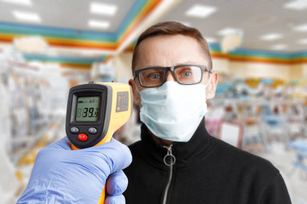 비접촉 온도계를 가진 의료 마스크에 있는 남자의 체온 측정 - 2675 뉴스 사진 이미지