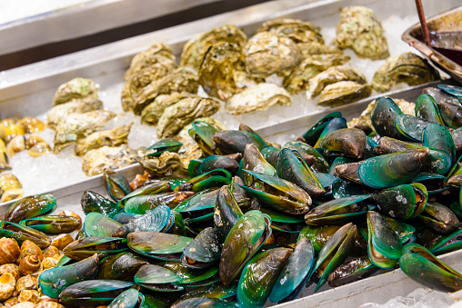 Green lipped mussels and other seafood for sale at a fishmonger stall in a Thai wet market, Thailand.