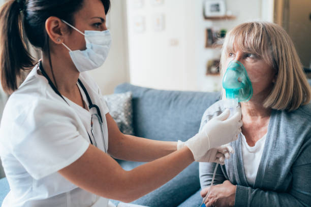 Doctor's home visiting during the quarantine Medical doctor applying medicine inhalation treatment on senior woman by the mask of inhaler during coronavirus quarantine breathing device stock pictures, royalty-free photos & images