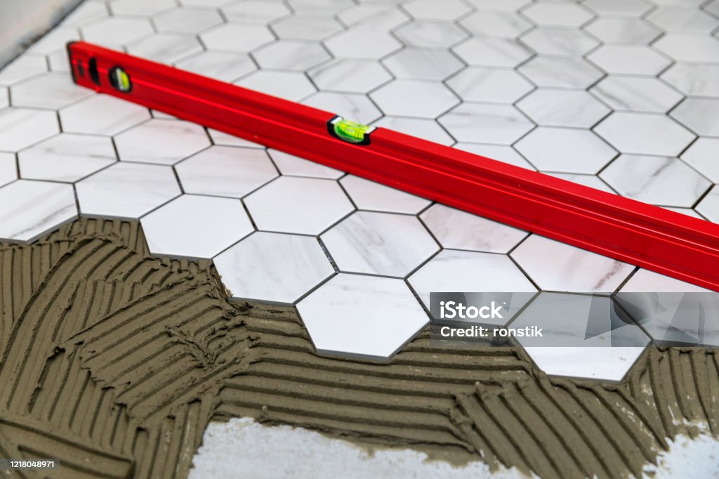 tiling - laying marble texture hexagon tiles on the floor Glue Stock Photo