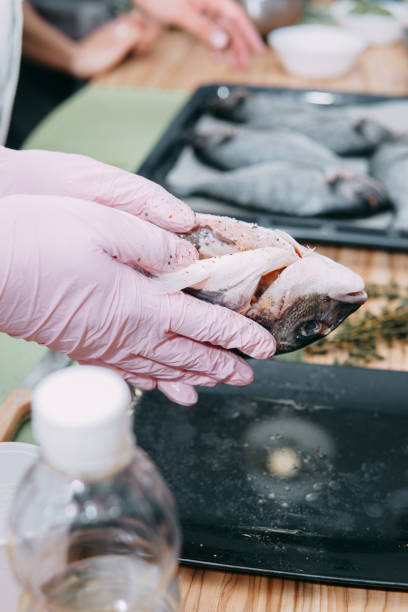 istock Raw Dorado fish on a black plate. Cooking Dorado in a cooking class. Raw fish, selective focus. Homemade food, cooking at home. Hands in the frame, the process of cooking fish. 1218050865