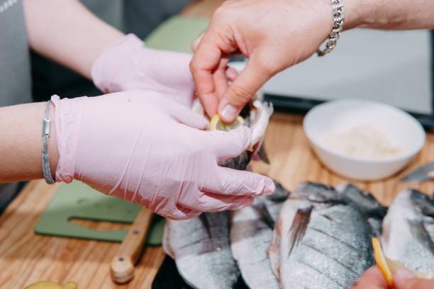istock Raw Dorado fish on a black plate. Cooking Dorado in a cooking class. Raw fish, selective focus. Homemade food, cooking at home. Hands in the frame, the process of cooking fish. 1218050915