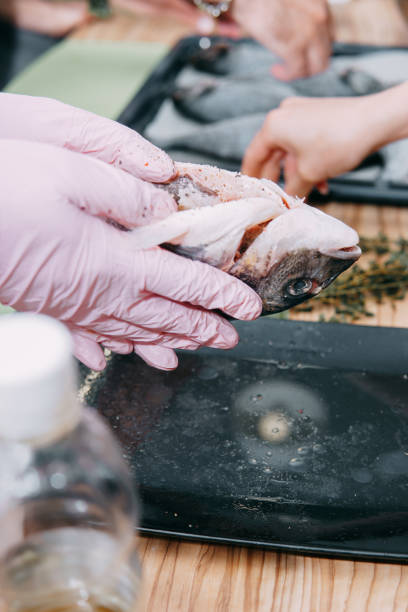 istock Raw Dorado fish on a black plate. Cooking Dorado in a cooking class. Raw fish, selective focus. Homemade food, cooking at home. Hands in the frame, the process of cooking fish. 1218051084