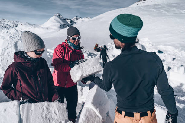Friends carve snow to build igloo