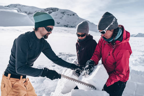 Friends carve snow to build igloo
