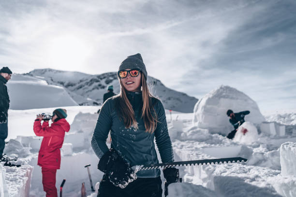 Young woman carves snow to build igloo She smiles as it is near completion igloo stock pictures, royalty-free photos & images