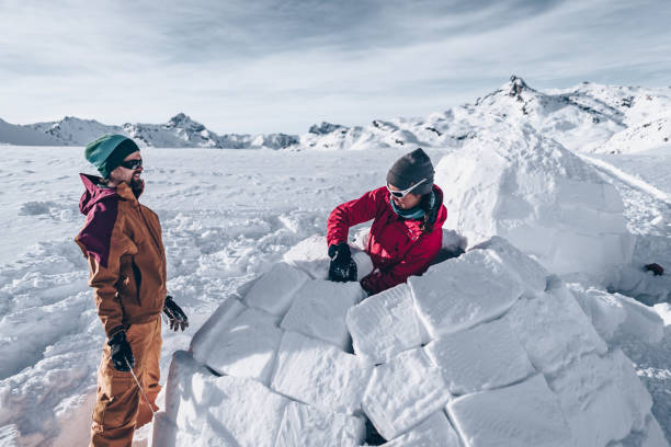 amigos tallan nieve para construir iglú - iglú fotografías e imágenes de stock