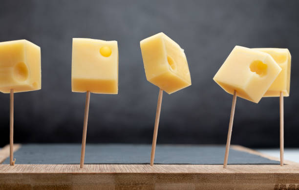 portions (cubes, dice) of emmental swiss cheese punctured in toothpicks. - cheese emmental cheese swiss culture cutting board imagens e fotografias de stock