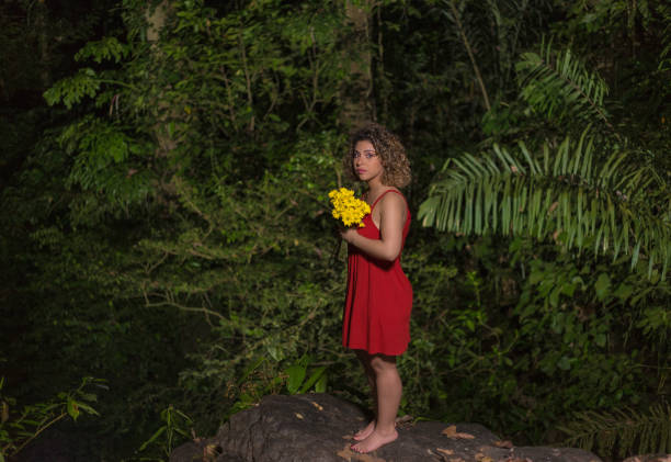 frau in rotem kleid und gelben blumen schießen porträt - tropical rain forest flash stock-fotos und bilder