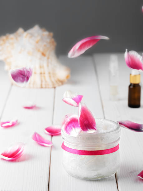 木製の白い背景上の代替療法のためのココナッツオイル。ピンクの花びらの花がテーブルの上に落ちています。クローズアップ。 - aromatherapy oil massage oil alternative therapy massaging ストックフォトと画像
