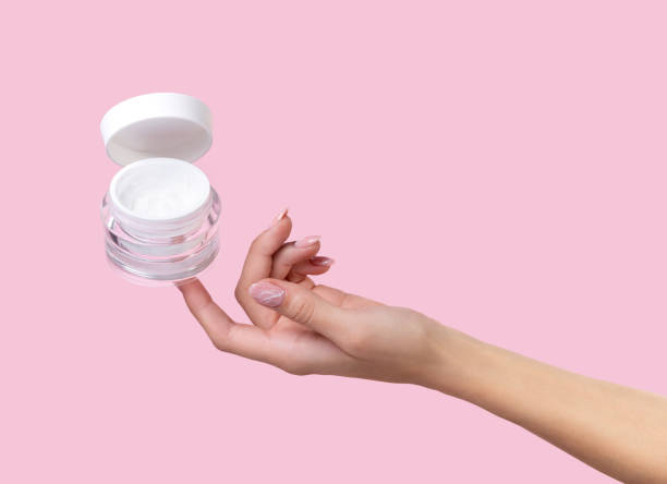 istock Open jar with cosmetic cream with womans hand on pink background 1218062387