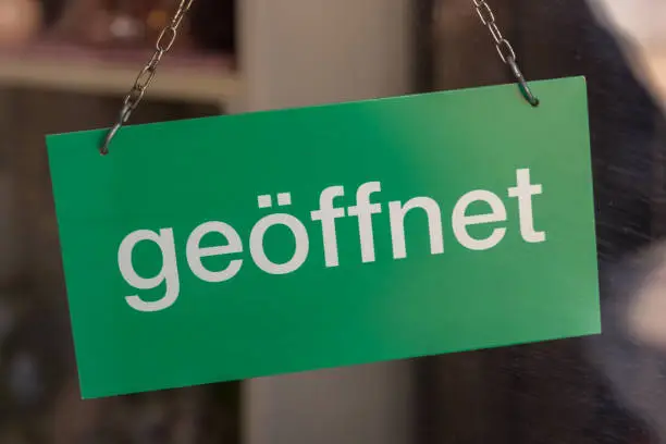 closeup of a green sign in a store with the german word open