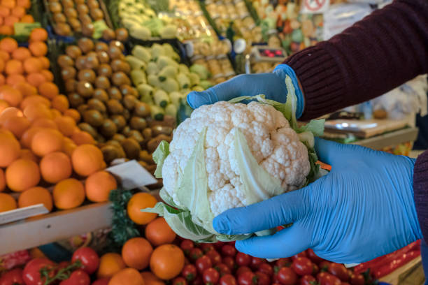 Greengrocer holding vegetables with rubber gloves during an epidemic of an infectious disease.