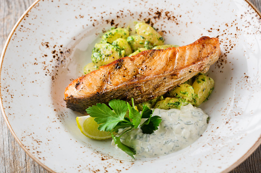 Grilled Salmon with Gnocchi and tartare sauce on white plate