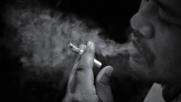 istock Man smoking cigarette and exhaling smoke in black and white style 1218068130