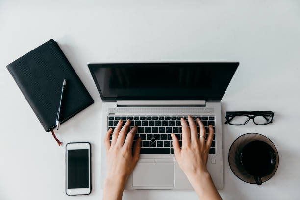 Freelancer workplace on a white background and hands with place for text. Top view. Laptop, glasses, cup and phone. stock photo