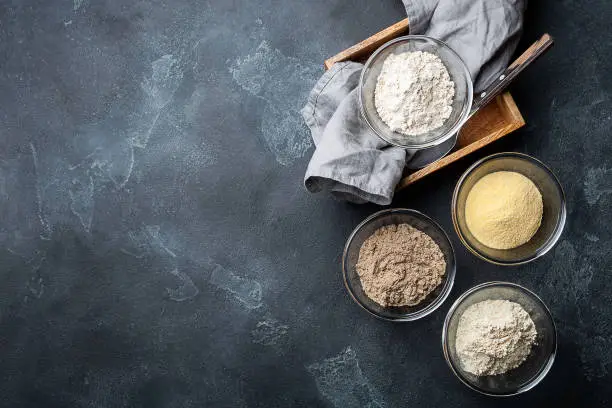 Photo of Various vegetable gluten free flour corn,sesame,oat,coconut in glass bowl on dark gray background