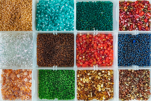 Palette of colors beads in the plastic box close up flat lay. DIY