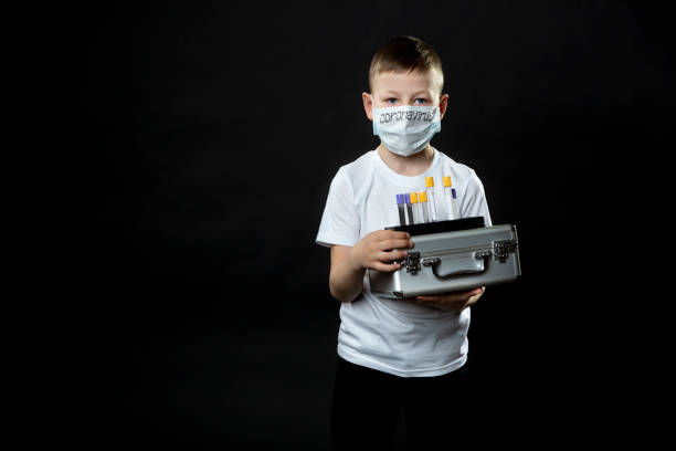 мальчик держит металлический чемодан. ребенок осматривает медицинскую пробирку с образцом вируса. мальчик осторожен с вирусом. коронавиру - engraved image surgery isolated metal стоковые фото и изображения