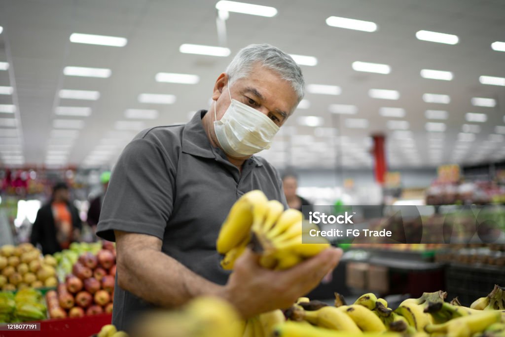 Senior man with disposable medical mask shopping in supermarket Protective Face Mask Stock Photo