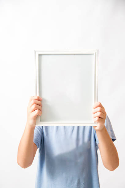 istock Boy holding up a blank picture frame 1218077545