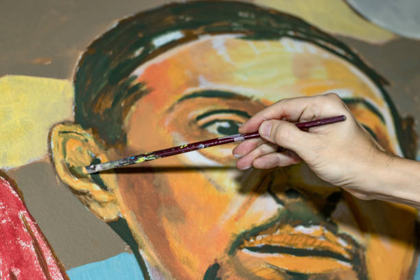 One man, painting in his home studio,, holding his brush, part of.