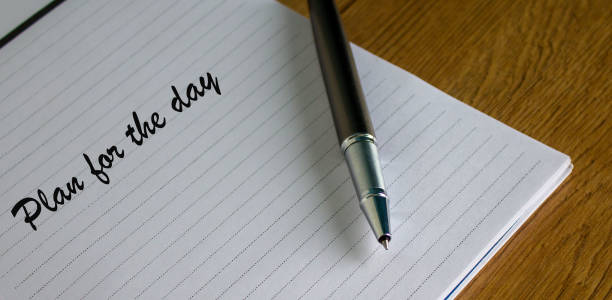 istock Notebook with the inscription plan for the day and pen on wood table. 1218078895