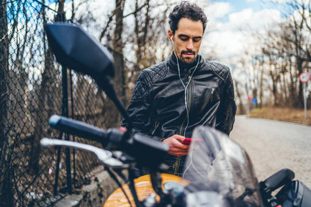 jeune homme beau de motard utilisant le téléphone mobile - electric motor audio photos et images de collection