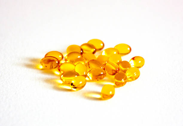 витамин d в таблетках на белом фоне. много желтых четких капсул - d3 стоковые фото и изображения