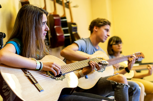 A group of students learn how to play guitar
