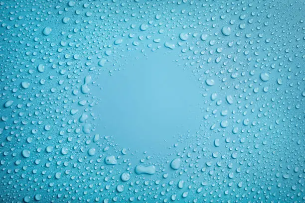Circle frame of water drops on blue background. Copy space